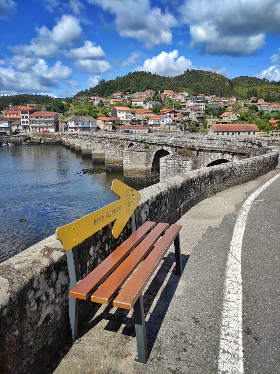 Stadt und alte Brücke auf dem Caminho Portugues Küstenweg -Typische Pilgerbank in Spanien - schmetterlinga